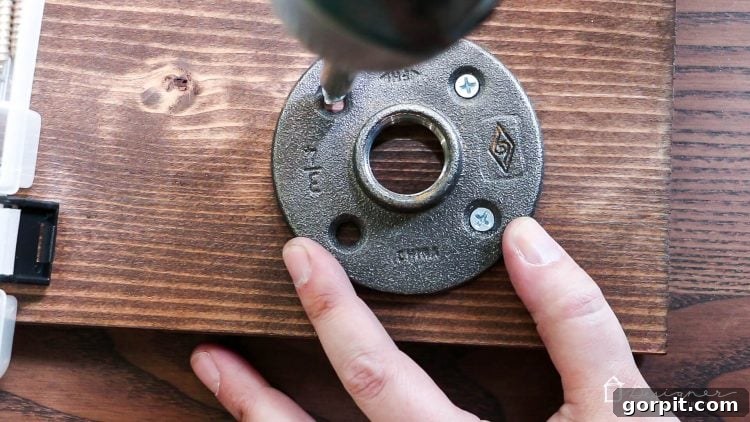 Four steel floor flanges are screwed into each corner of the underside of the stained wooden top board.