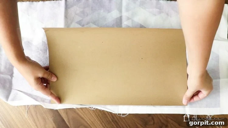 Carefully pressing fabric onto Mod Podge-coated chipboard, ensuring smooth adhesion.