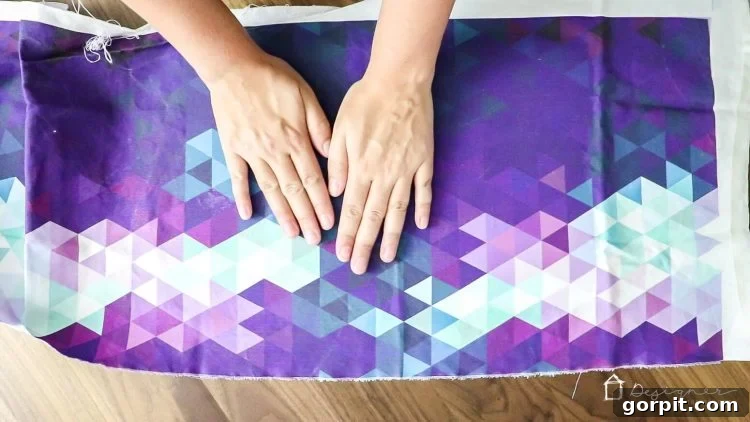 Smoothing out wrinkles on the fabric-covered chipboard with hands, achieving a flat surface.