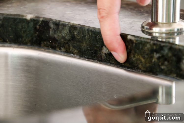 Seamless Caulk Replacement Guide 4 Before caulk replacement: Dirty, cracked caulk around a kitchen sink, ready for a DIY refresh.
