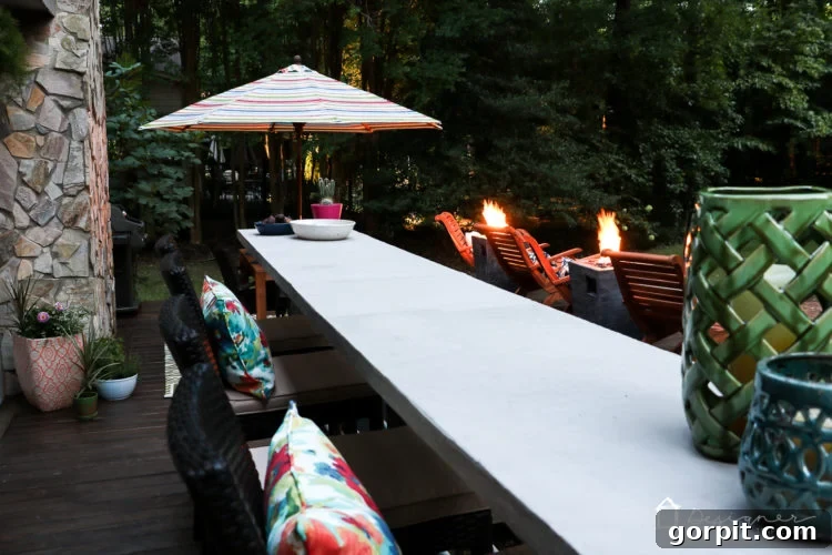 A serene evening scene on the deck, highlighting the cozy atmosphere created by the furniture arrangement, soft lighting, and the warm glow of the fire columns.