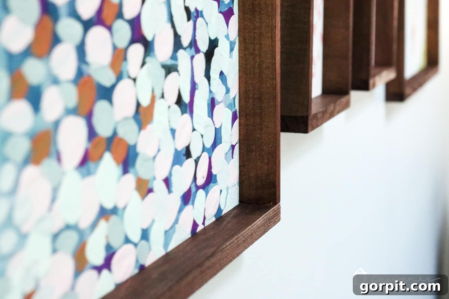 Crafting Stunning Frames for Your Big Art 12 A close-up of the bottom right corners of DIY picture frames stained deep brown. The frames are hung on a wall and seen at an angle.