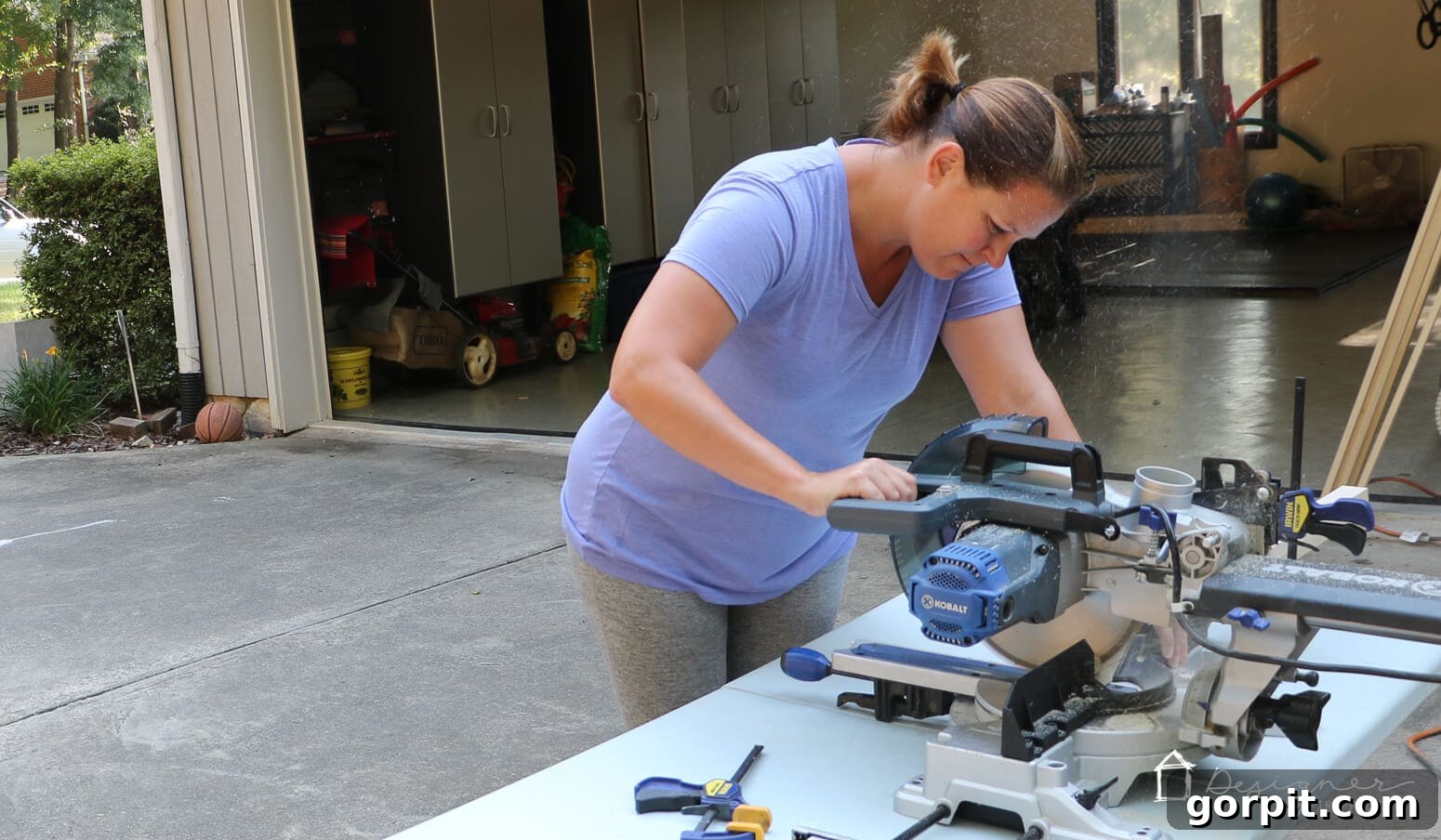 Crafting Stunning Frames for Your Big Art 3 Tasha from Kaleidoscope Living uses a saw to cut down wood for an art frame in her driveway to demonstrate how to make a picture frame.