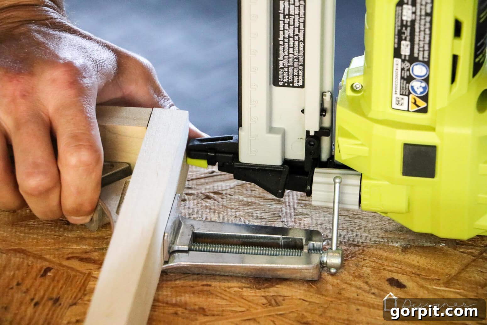 Crafting Stunning Frames for Your Big Art 6 A close-up of a person using a nail gun to attach two pieces of wood together to make a DIY picture frame for larger art prints.