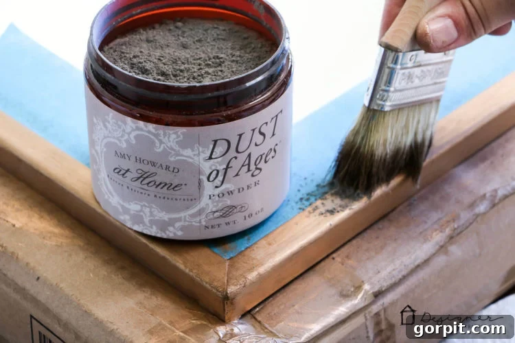 Dusting Amy Howard At Home Dust of Ages over the dark wax to enhance the antique gold finish on the mirror frame.