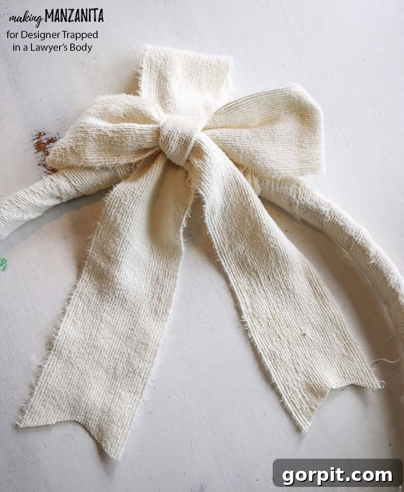 Adding a fabric hanger and bow to the top of a finished DIY boho winter wreath