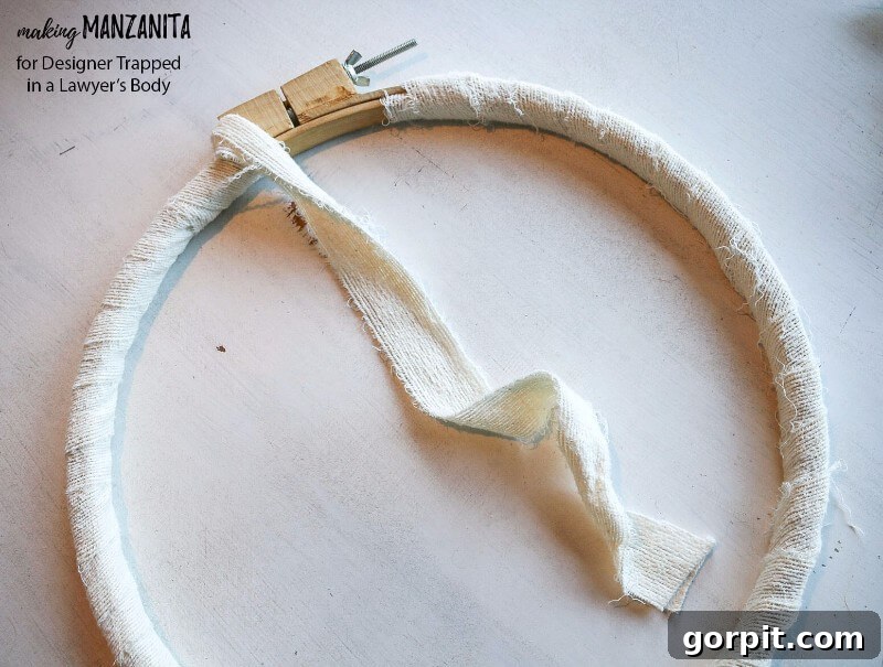 Wrapping an embroidery hoop with white fabric strips for a DIY winter wreath