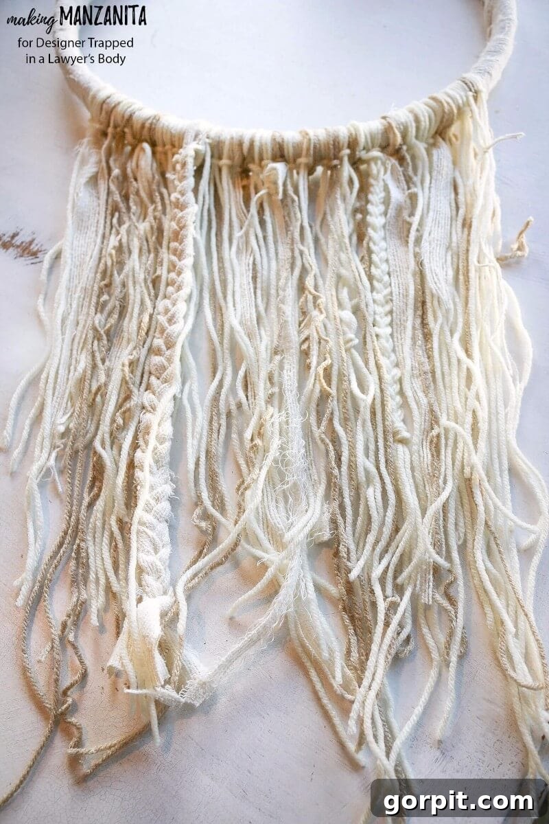 Detail shot of various yarn and fabric textures forming the base of a DIY boho winter wreath