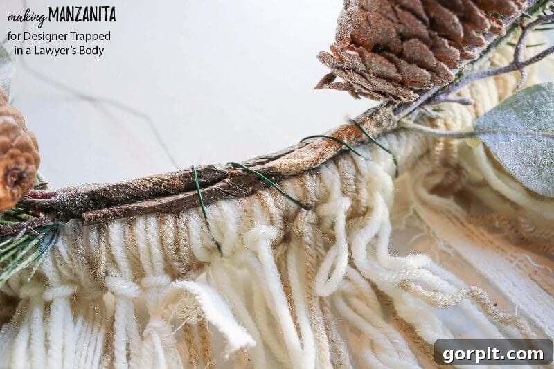 Attaching frosted floral picks to the embroidery hoop base of a DIY winter wreath