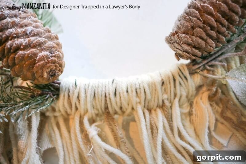 Covering floral wire with yarn on a DIY boho winter wreath for a neat finish