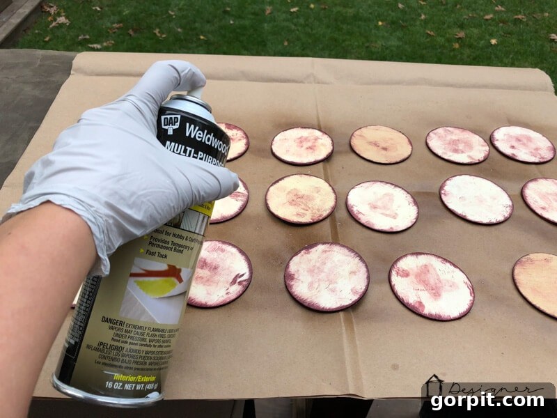 Applying spray adhesive to a wood disc in preparation for attaching a photo for a DIY Christmas ornament.