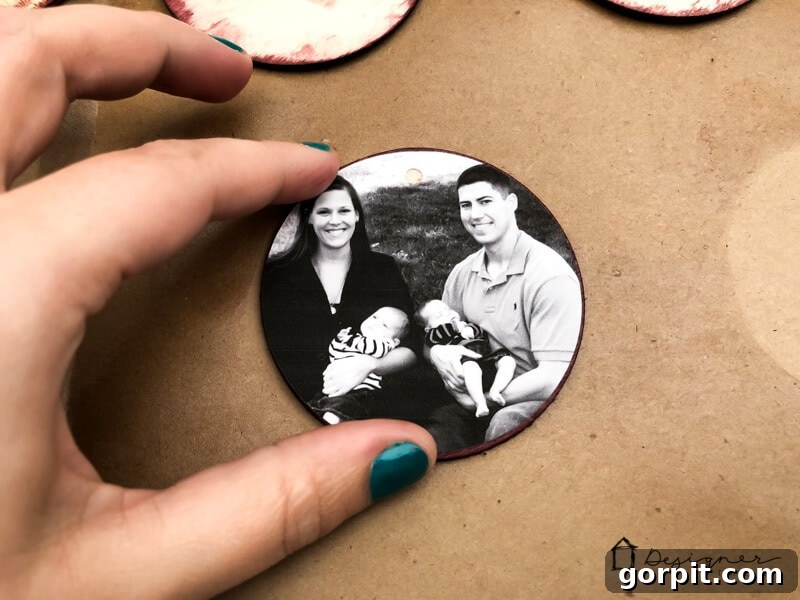 A family photo being carefully placed onto a wood disc, creating a DIY Christmas ornament.