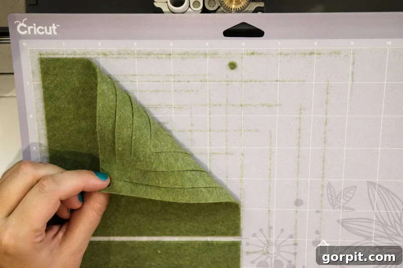Warm & Fuzzy Holidays: Crafting One-of-a-Kind Felt Ornaments 4 Using transfer paper on a Cricut cutting mat to prevent felt fibers from sticking, ensuring a clean mat and perfect cuts for DIY ornaments.