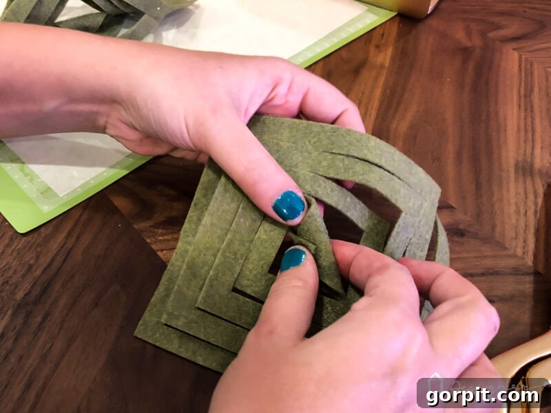 Warm & Fuzzy Holidays: Crafting One-of-a-Kind Felt Ornaments 7 Continuing the DIY felt Christmas ornament assembly: securing the initial fold with hot glue for a clean, professional finish on your handmade decorations.