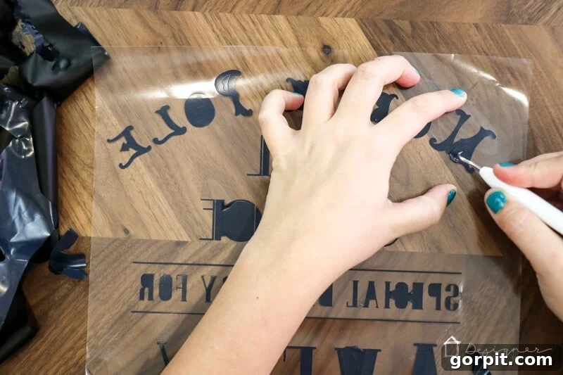 Woman carefully weeding a heat transfer vinyl design cut with a Cricut machine, revealing intricate details