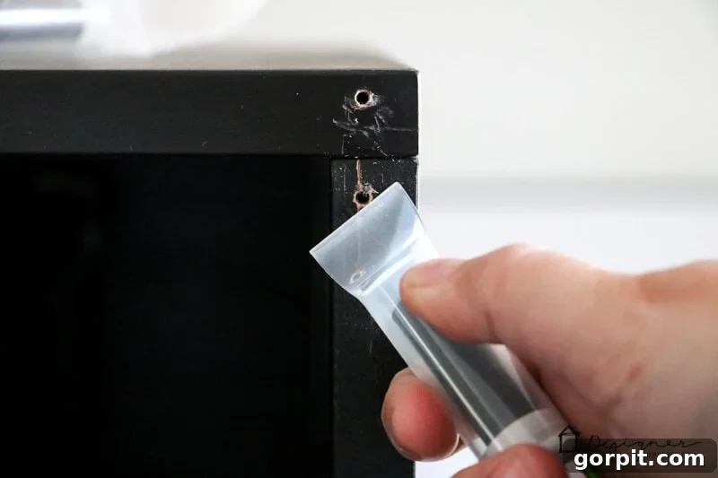 A close-up shot of a hand meticulously using the Leveler Cap from the Mohawk 3-in-1 Repair Stick to smooth out and clean up damage on IKEA furniture, demonstrating an easy and budget-friendly repair method.
