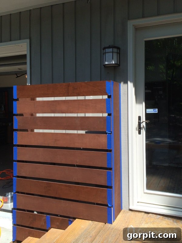 Applying painter's tape around the area where a screw will be driven into pre-stained wood, protecting the surrounding finish.