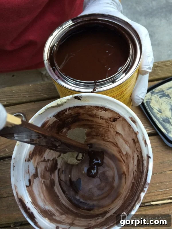 Close-up shot of wood filler being mixed with wood stain in a small dish to create a custom color match for pre-stained wood repair.