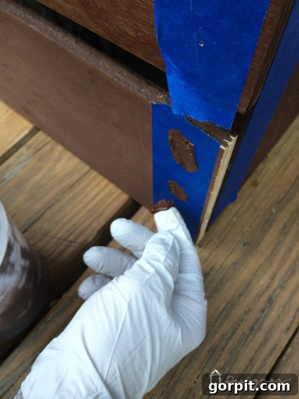 The final result of a filled screw hole on pre-stained wood after painter's tape has been removed, showing a seamless, color-matched repair.