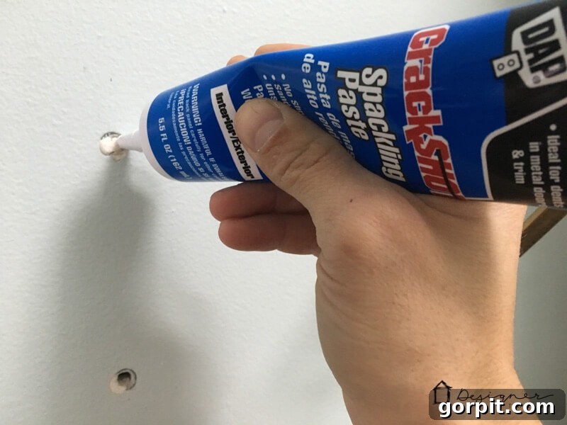 Applying spackling paste to a small hole in the wall with a putty knife.