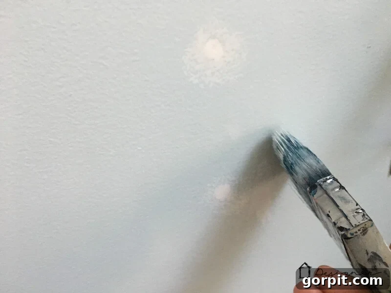 Touching up the paint after a successful drywall repair.