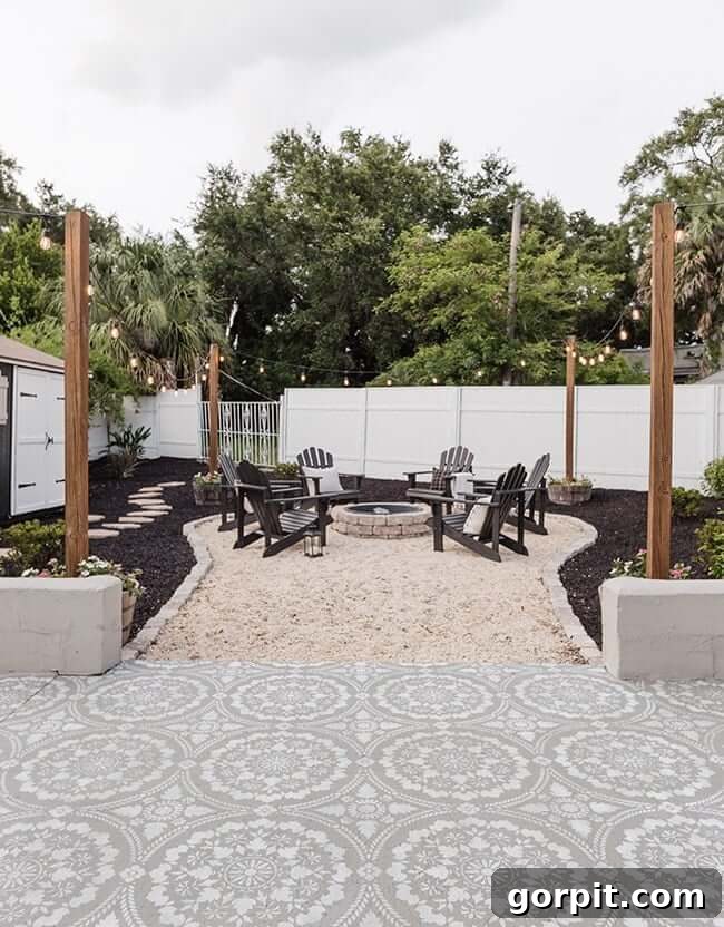 A fire pit off of the patio with a border of retaining wall blocks, blank chairs, and poles with lights, creating a cozy and well-defined outdoor area.