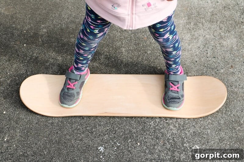 A child standing on a skateboard deck, indicating where to mark for rope holes, with safety in mind.