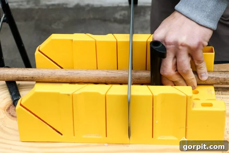 Close-up of a hand saw cutting a dowel rod, demonstrating the process of preparing swing handles.