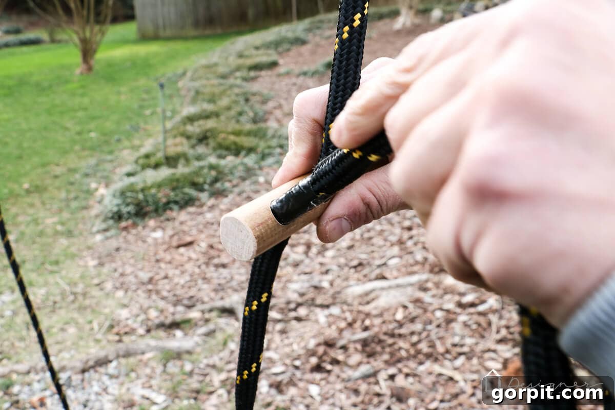 Detailed view of rope being threaded through the two holes of a wooden handle for adjustable height.