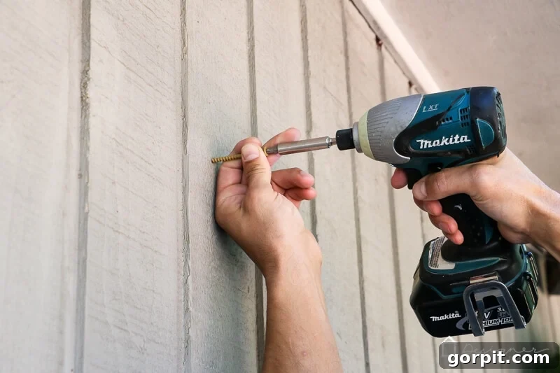 Build a Custom Outdoor Chalkboard 11 A hand securing a screw into a wooden wall to hang the outdoor chalkboard
