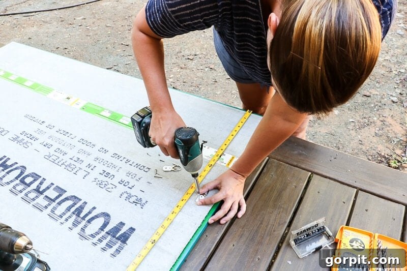 Build a Custom Outdoor Chalkboard 9 A person attaching D-ring hangers to the back of the wooden chalkboard frame