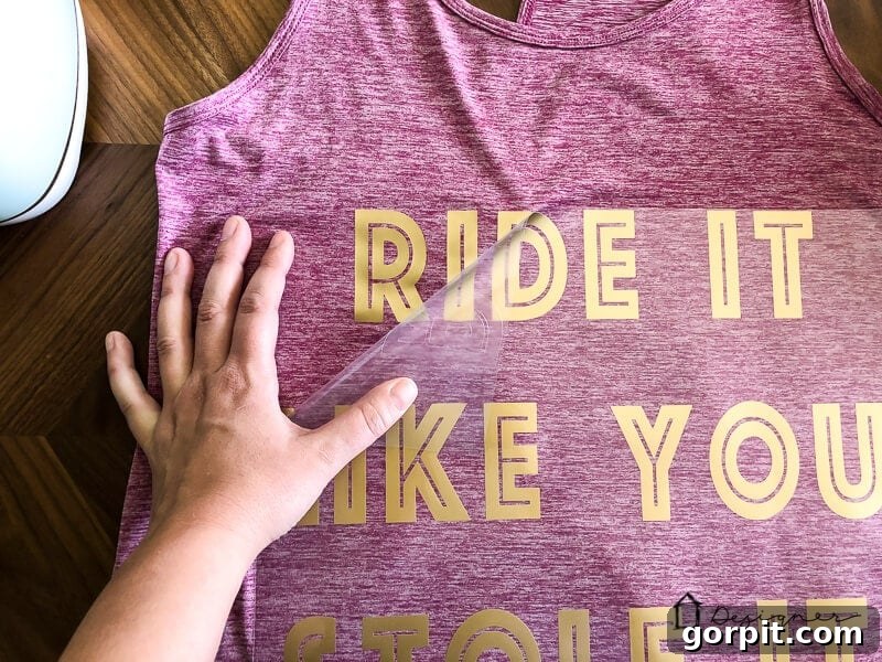 The exciting reveal: peeling the carrier sheet after cold-peel application of Cricut SportFlex Iron On for a custom workout shirt.