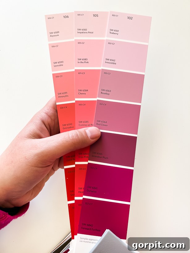 Three paint chips showing similar light red and pink colors, highlighting the difficulty of choice at lighter hues.