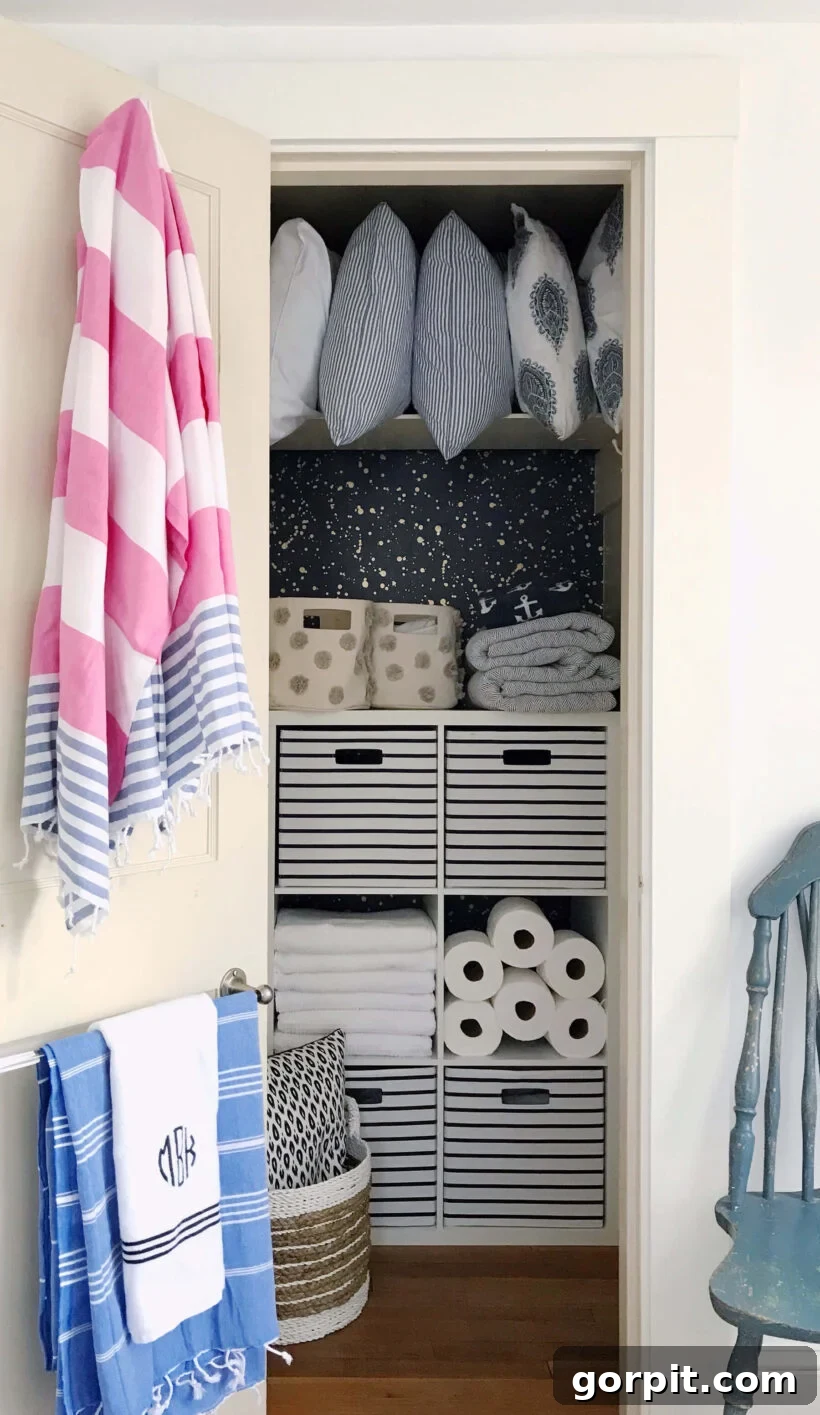 linen closet with wallpaper and shelf unit for organization