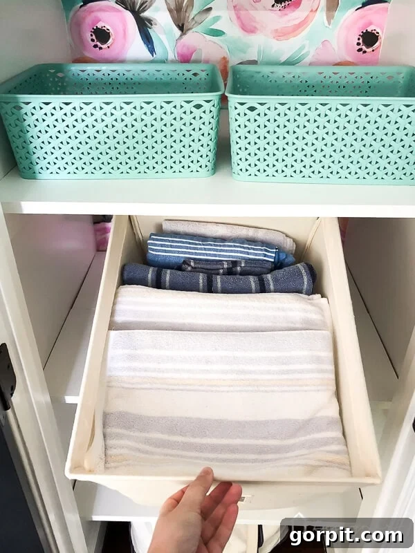 photo of towels stored in canvas bins to help keep linen closet organized