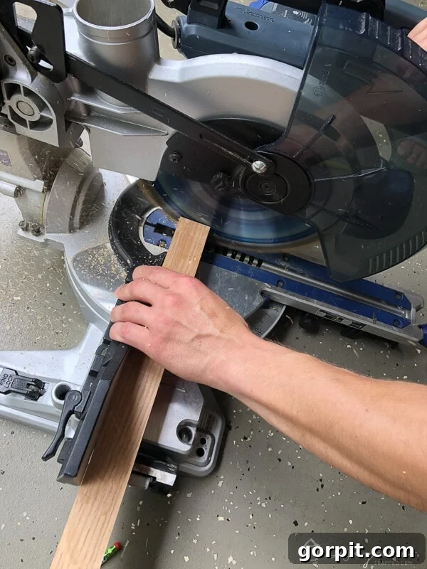 Tangle-Free Treasures: Easy DIY Jewelry Organization 4 Person using a compound miter saw to cut a 2x2 wood piece for corner blocks.