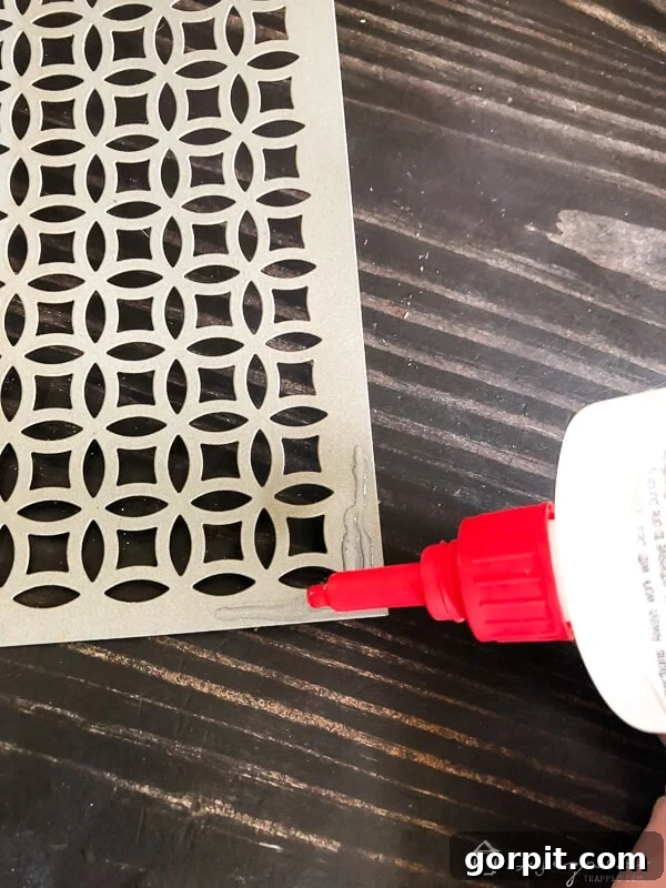 Tangle-Free Treasures: Easy DIY Jewelry Organization 6 Applying DAP Rapid Fuse glue to the corner of a decorative aluminum sheet.