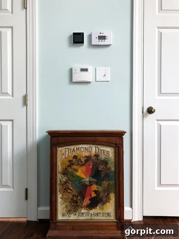 Unsightly wall area with thermostat and alarm pad before DIY art transformation