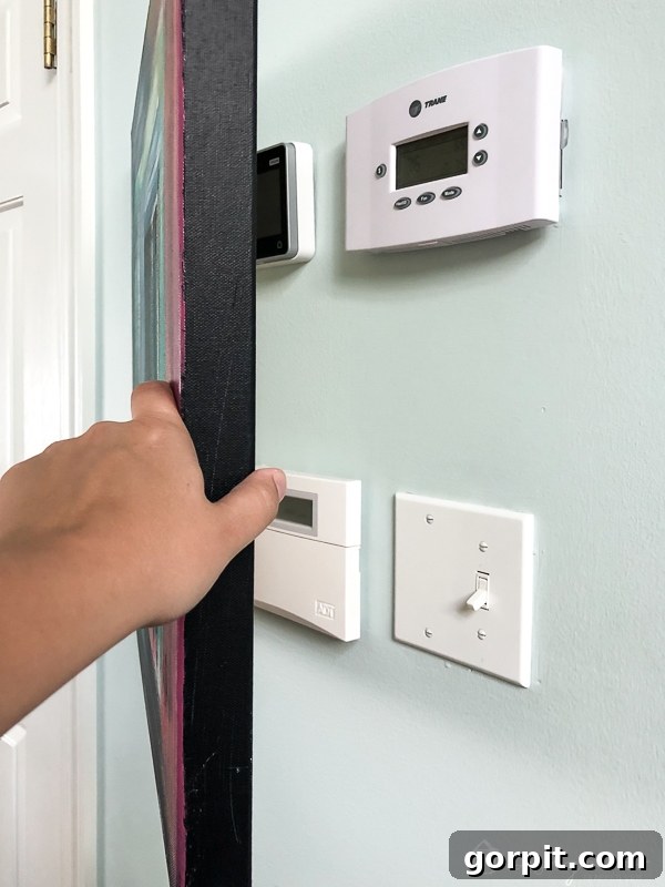 Abstract art panel concealing thermostat and alarm system on the wall