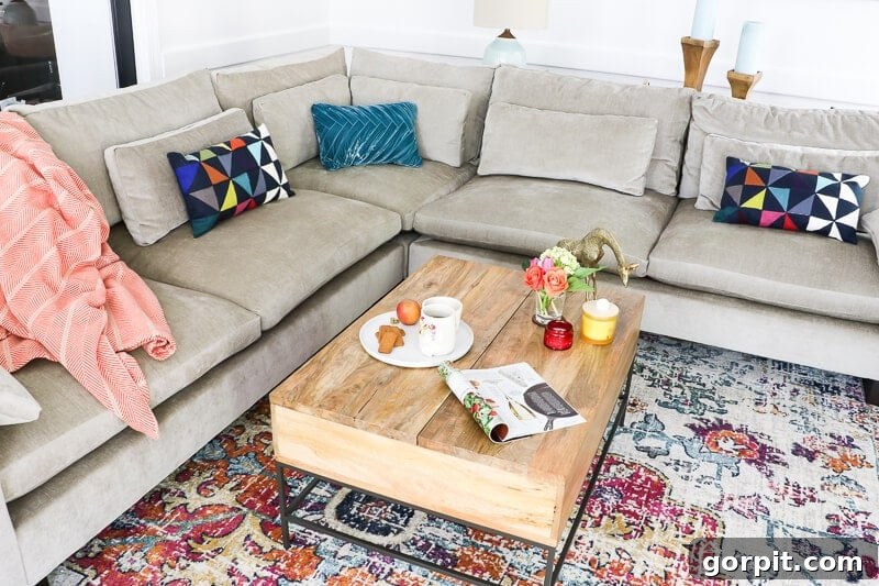 Sofa Freshness Hacks 3 A West Elm Harmony Sectional Sofa with fabric protection on top of a large colorful area rug with a wood coffee table. Bright pillows dot the couch.
