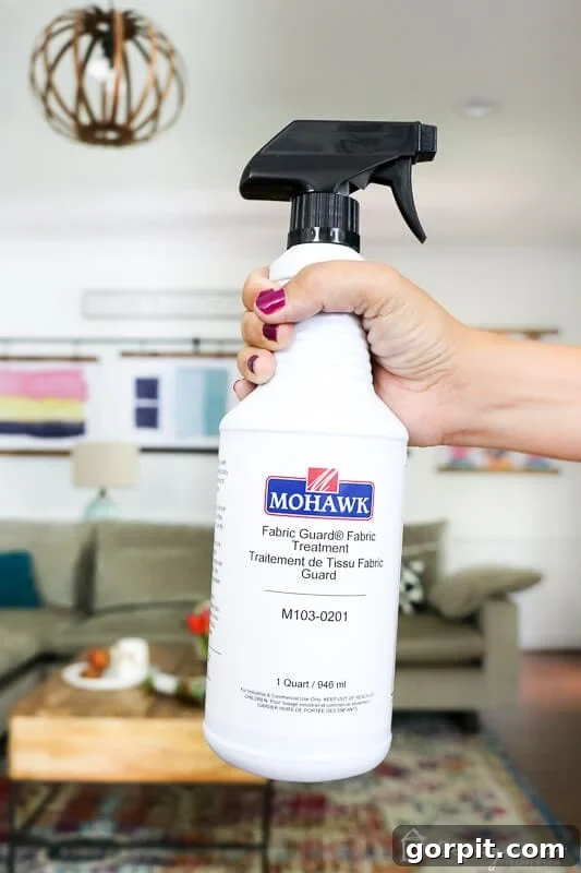Sofa Freshness Hacks 4 A woman's hand holds a spray bottle of Mohawk Fabric Guard, a recommended fabric protection product.