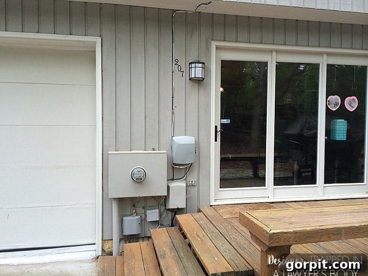 DIY Outdoor Electrical Box Enclosure 3 image of cluster of utility boxes hanging on outside of contemporary house by back door
