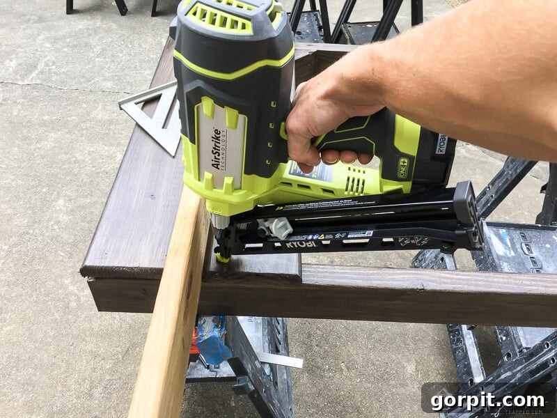 DIY Outdoor Electrical Box Enclosure 7 photo of nail gun attaching horizontal slats to outdoor gate door
