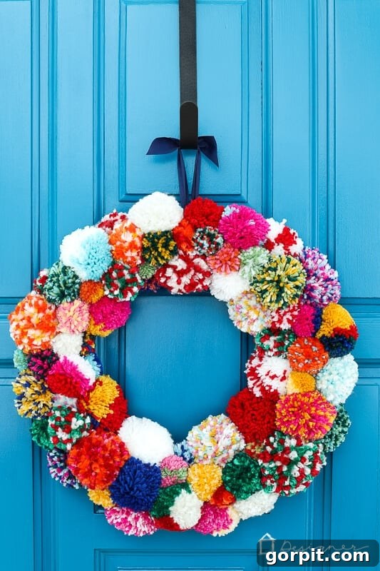Beautiful, finished colorful pom pom wreath displayed on a door