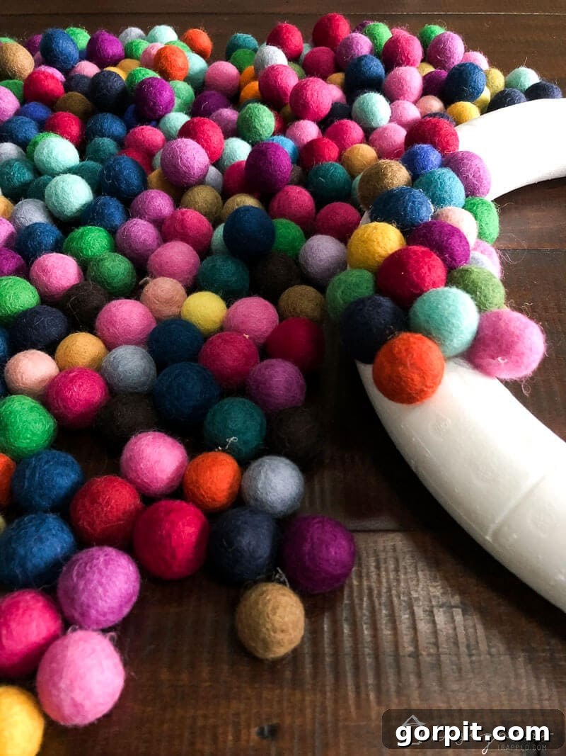 A colorful DIY felt ball wreath in progress, showcasing the vibrant felt balls covering the front and sides of the foam form