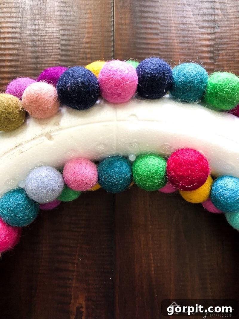 The back view of the felt ball wreath, showing felt balls covering the inner and outer curves but leaving the very back flat for hanging