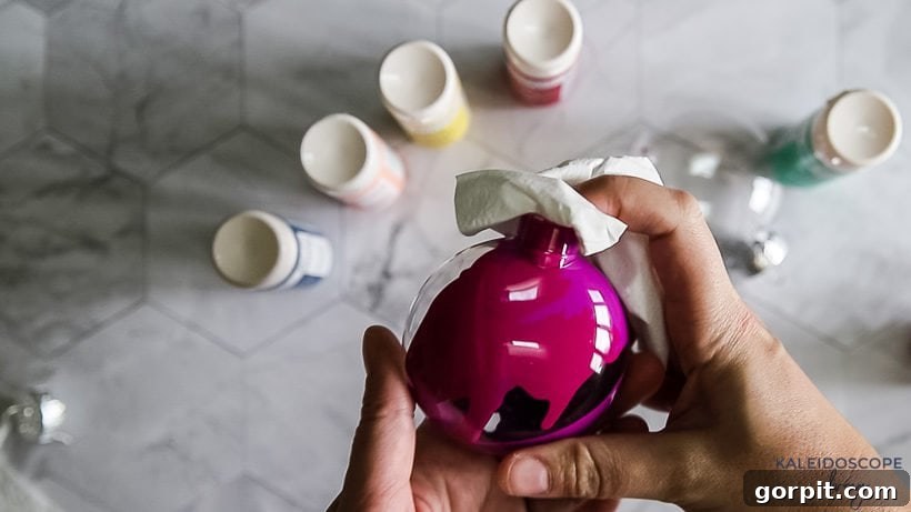 Vibrant and Effortless Christmas Crafting 5 A clear plastic ornament with two distinct colors of acrylic paint swirled inside, demonstrating the marbling effect.