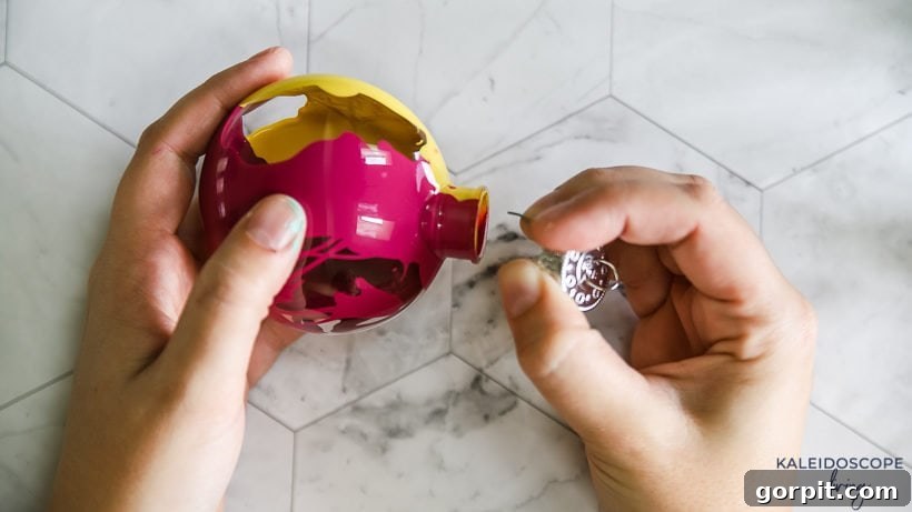 Vibrant and Effortless Christmas Crafting 7 A hand reattaching the metal hanger to a finished, dry, and beautifully marbled Christmas ornament.