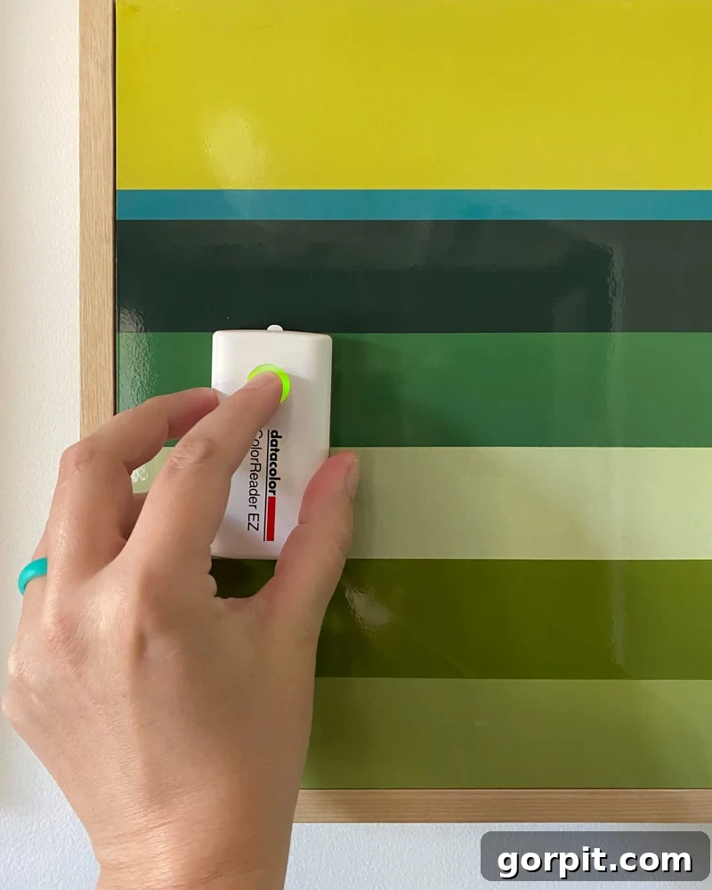 Datacolor ColorReader EZ device being used to match a paint color on a wall, showcasing its small size and ease of use.