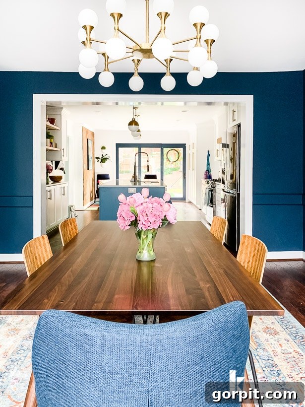Open concept view of a navy blue dining room seamlessly transitioning into a modern kitchen